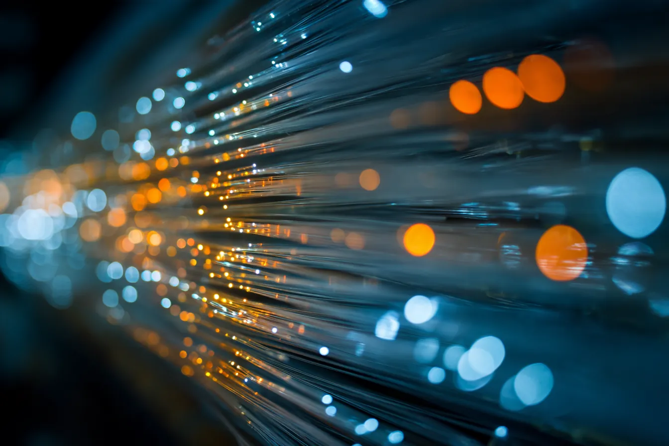 Close-up of glowing fiber optic cables in a dark server rack, shallow depth of field