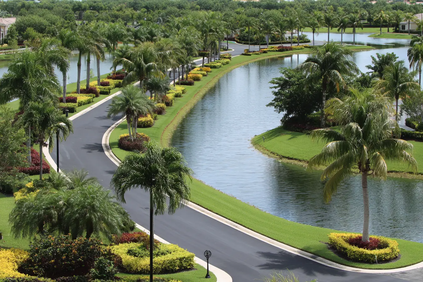 Manicured common grounds of a Southwest Florida community, royal palms lining a curving road beside a calm lake
