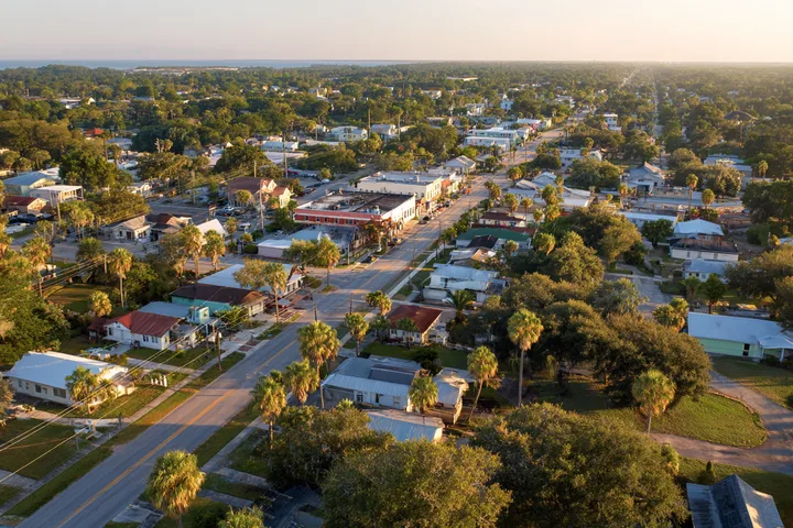 Aerial view of a small Florida town grid of streets, rooftops and palms in golden hour light
