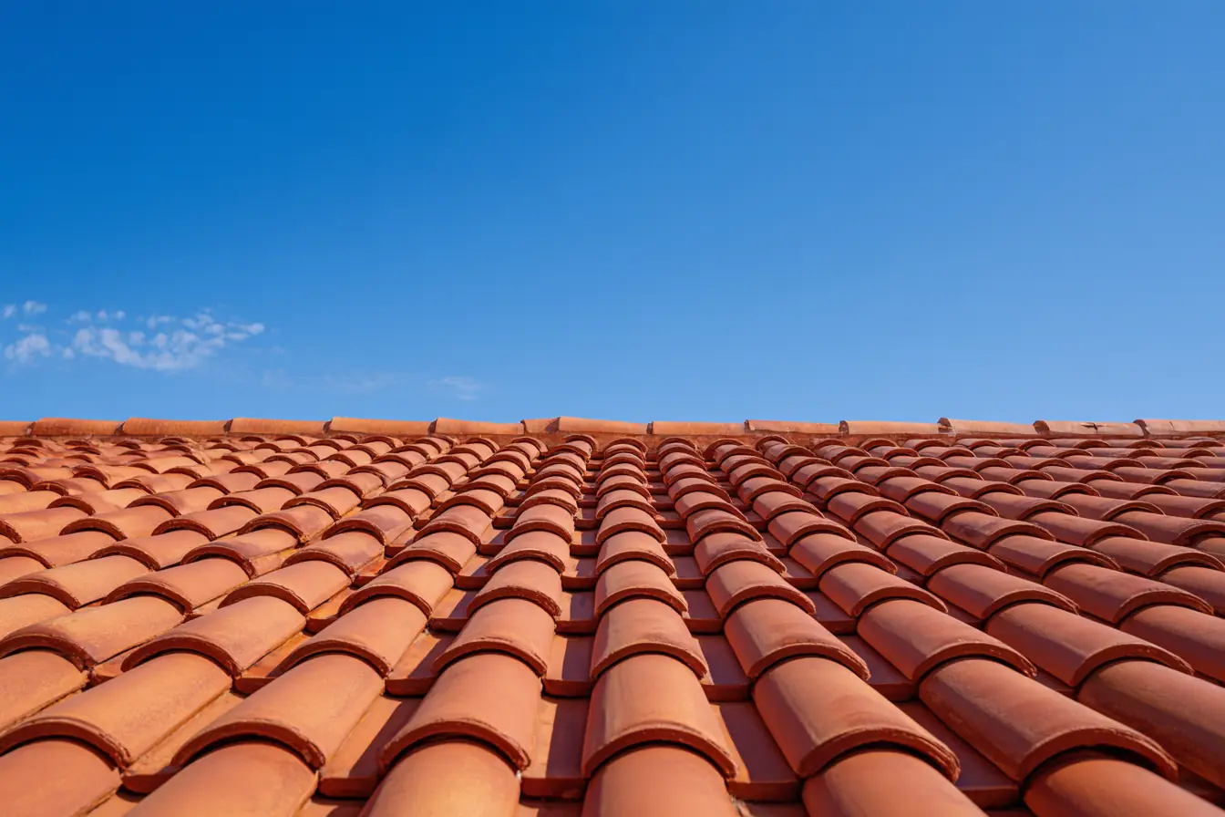 Clean terracotta barrel roof tiles after a soft wash, under a clear blue sky