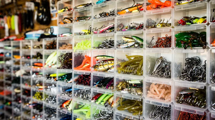 A wall of clear bins sorted by kind of fishing lure and hook in a tackle shop