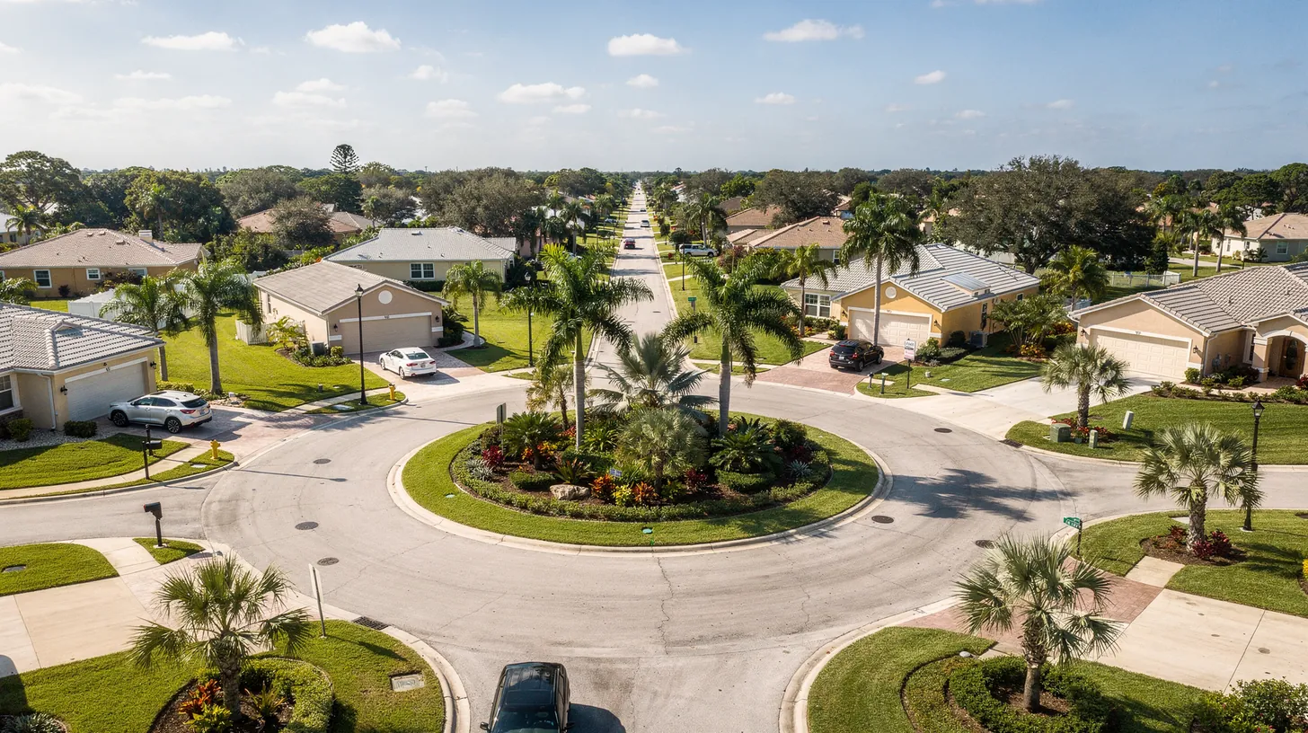 An aerial view of a landscaped roundabout with streets leading out to neighborhoods of tile-roofed homes