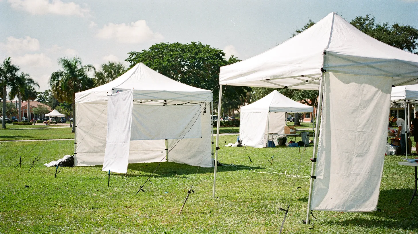 White pop-up tents set up on a park lawn ahead of a community event